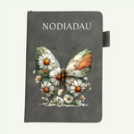 A dark gray notebook with a decorative butterfly and daisy design on the cover, featuring the word 'NOTEBOOK' printed at the top.
