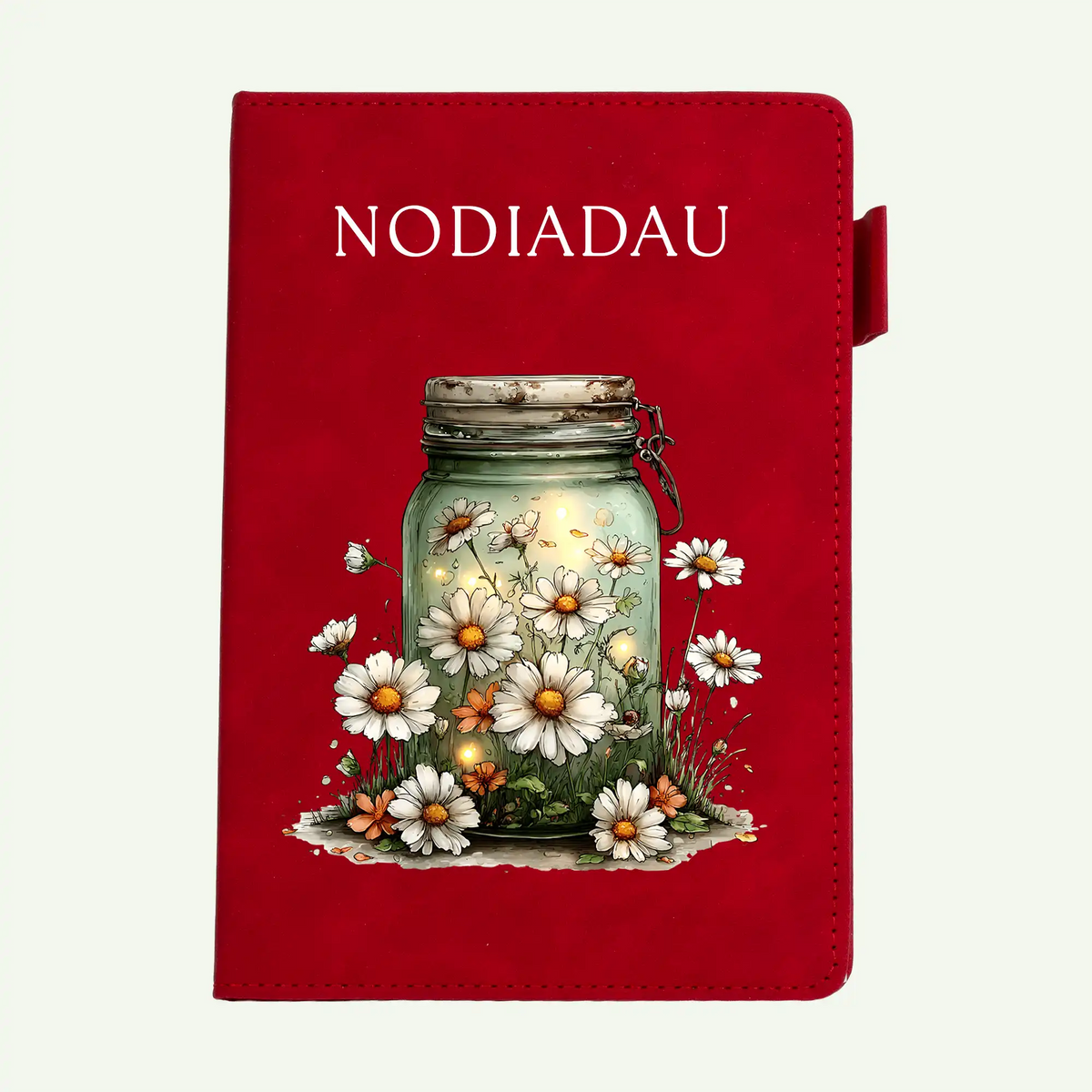 A red hardcover journal or notebook featuring the word 'NODIADAU' in white serif text at the top and an illustration of a glass jar filled with glowing light, surrounded by white daisies and small orange flowers on the front cover.